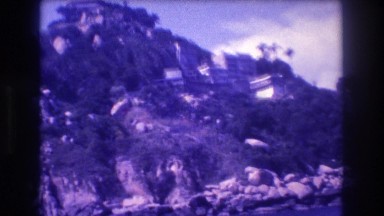 1982: homes under a cloudy blue sky, set against a lush green countryside hill
