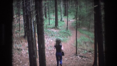 1975: a woman and a dog running along a trail through the woods BAXTER MAINE