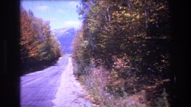 1975: distant view of a blue mountain down a sloping road