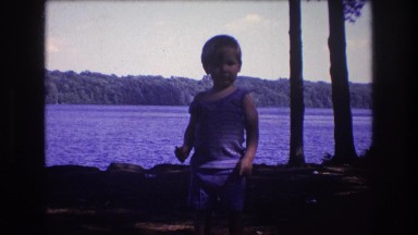 1975: baby walking looks happy waving pretty near water. standing on the ground.