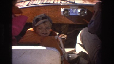 1975: kids in life jackets sitting in the front seat of a boat sailing through