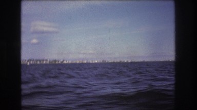 1975: the coastline and pier over the water as seen from a moving vessel BOSTON