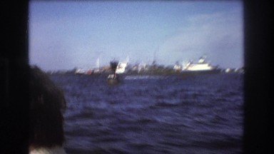 1975: people riding along on a boat. BOSTON