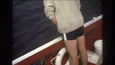 1975: guy standing on boat river water fixing something wearing shorts