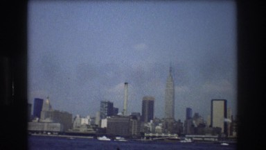 1976: viewing of a large city with a lake in front of the buildings. NEW YORK