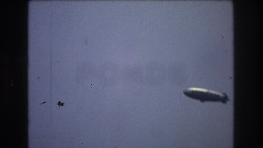 1976: Silver Blimp Flies Over New York City Harbor and Sailing Ship at Sea