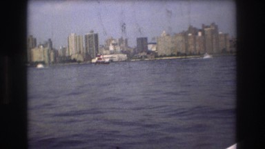 1975: a boat with woman in harbor traveling next to a cruise ship