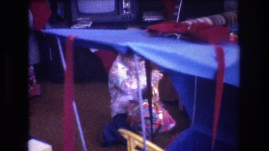 1975: little boy struggling to untie the bow on his christmas present BAXTER