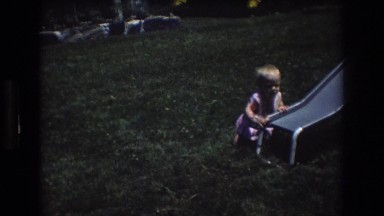 1976: child playing at the bottom of a slide trying to walk in a park MT BROMLEY