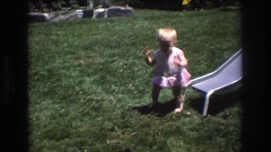 1976: baby playing on grass next to slide with man and dog
