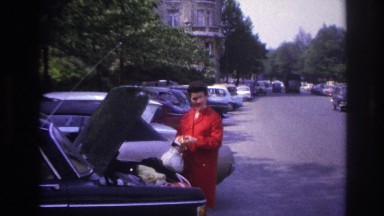 1967: a young beautiful lady in red dress standing near to the car parked PARIS