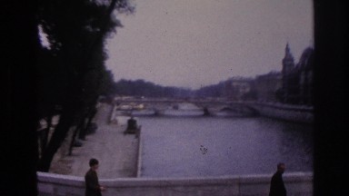 1967: viewing of a bridge with visitors walking alongside against a small city.