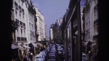 1967: view of a european city street packed with traffic and people walking on