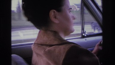 1966: woman carefully driving a large car, exiting time on a highway