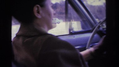 1966: a woman with black gloves driving a car down the highway HOBOKEN