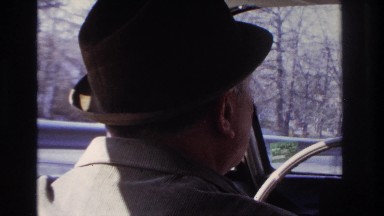 1966: man with hat driving car fast motion trees in background HOBOKEN