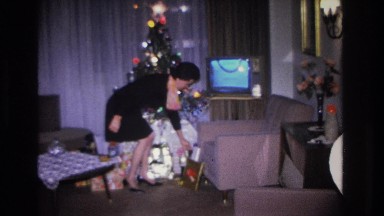1966: A Woman Takes a Seat on the Couch and Opens a Christmas Gift