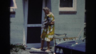 1962: elderly woman holding dog and moving lawn chair. RALEIGH NORTH CAROLINA