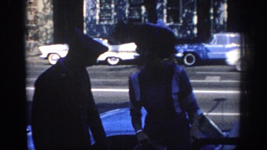 1967: Couple Walking Alongside a Street with Cars Moving Behind in Oklahoma