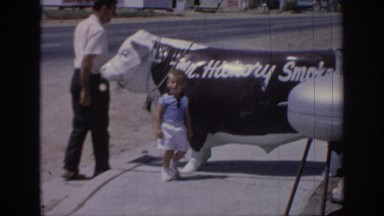 1967: man and young boy standing by a statue of a cow OKLAHOMA