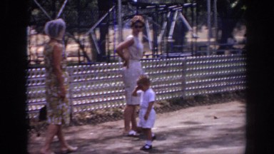 1966: Two Women in Floral Dresses and a Small Boy Wave at Camera in Sacramento Park