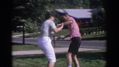 1967: suburban man spanks woman with a newspaper in the front yard