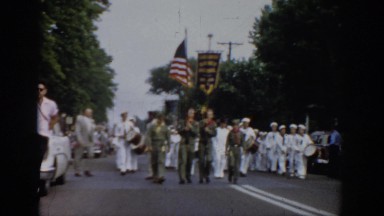 1965: a parade with men in navy uniforms carrying the united states flag through
