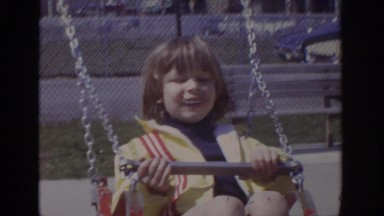 1973: a little girl in a yellow jacket swing on a swing set PHILADEPHIA