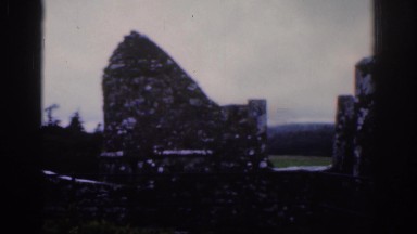 1961: two people taking a video near an iron fence like and old tower DUBLIN