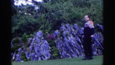 1961: a man posing before the camera framed by stones and a wooded area DUBLIN