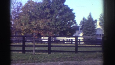 1976: farm with a house in the back, field surrounded by a brown wooden fence