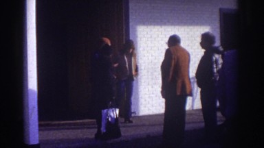 1976: some folks standing around outside a building WATKINS GLEN NEW YORK
