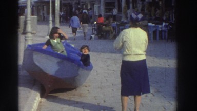 1976: Two Kids in a Boat on the Street While Their Mom Takes Pictures GREECE