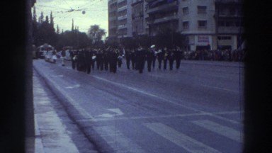 1976: Military Band Leads Traditionally-Dressed Marchers in Greek City Parade