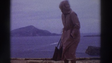 1976: Warmly-Dressed Woman Looks at Ancient Columns Elevated Above the Sea