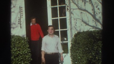 1976: Waving Man in White Shirt and Jolly Man in Red Sweater Leave from Door