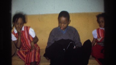 1975: three african american kids are sitting on a couch trying to wait