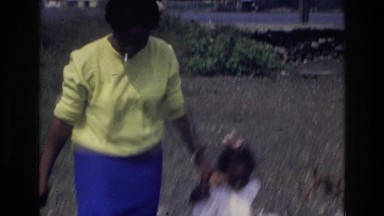 1976: mother and children playing together on beach with rocks and sand