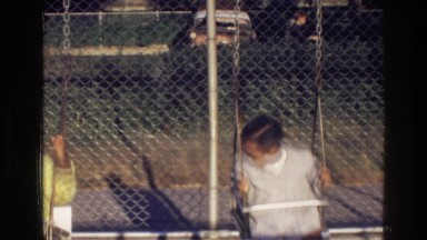 1976: children playing happily on a swing set at an elementary schools HARLEM