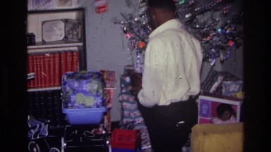 1976: Man Looking Through Christmas Presents in Harlem, New York