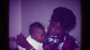 1976: mother carrying her child in hand, mom dancing with some food HARLEM