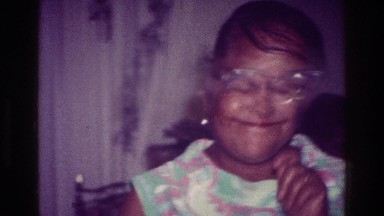 1976: a woman inside, holding a small plate of food and doing a little dance