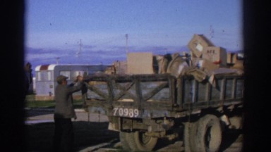 1963: Men Working to Close the Back Gate of an Old Truck Overflowing with Cargo