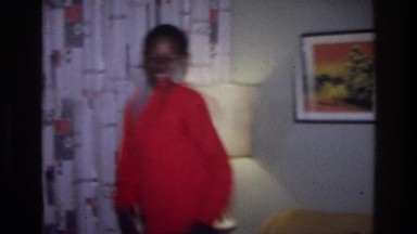1976: teenager walking across a living room smiling to other people HARLEM