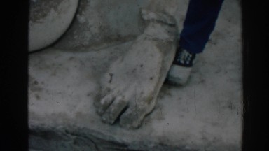 1962: man shows off at corinthian landmark with giant sculpted foot. EPHESUS
