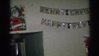 1962: Man Sitting Below Merry Christmas Sign in Gary Indiana