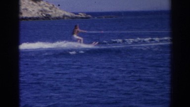 1962: a man water skiing behind a boat along a mountainous coastline IZMIR