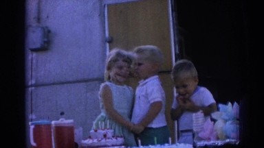1962: three young children at a party, hanging around the food, hugging