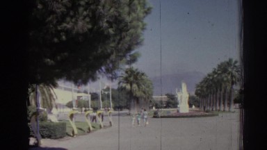 1962: people milling about in a courtyard with a statue and rows of trees IZMIR