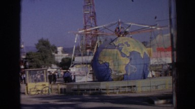1962: amusement park guests walk past a park ride that has a large globe